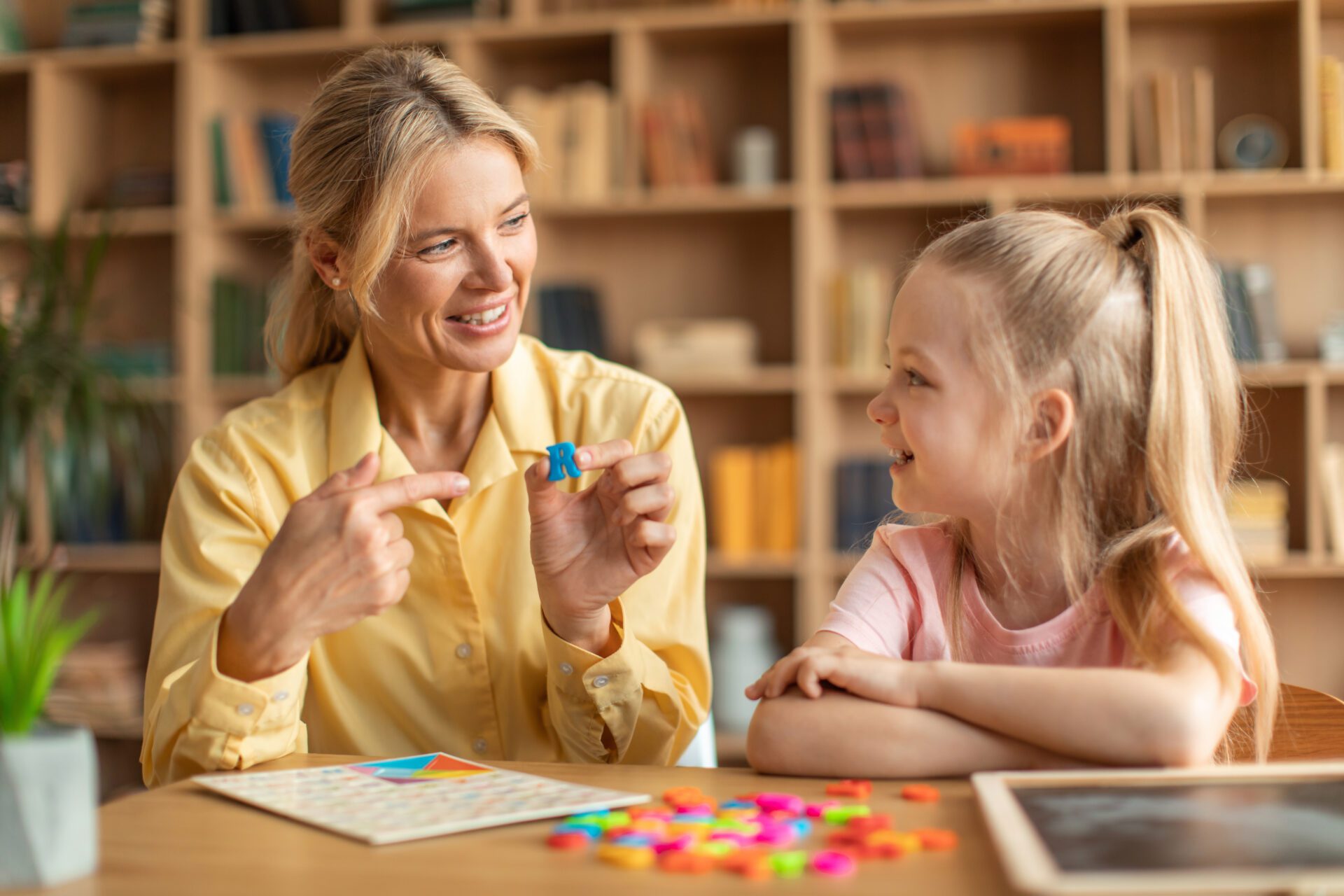Teacher and child crafting with colorful shapes