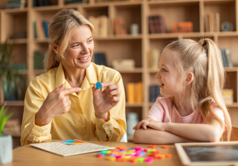 Teacher and child crafting with colorful shapes
